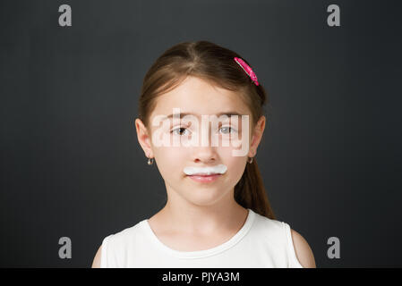 Jeune fille bénéficiant d''un verre de lait frais affichant une moustache blanche. Banque D'Images