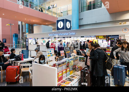 Japon, Osaka. L'Aéroport International de Kansai. KIX, une borne d'intérieur rez-de-chaussée, bureau d'informations touristiques avec des personnes en attente. Banque D'Images