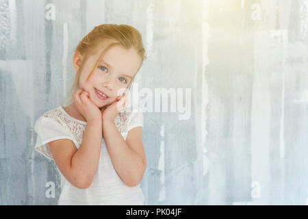 Sweet Little girl in blank white t-shirt standing against wall background texturé gris, les écoliers de la petite enfance, de la jeunesse, vous détendre concept Banque D'Images