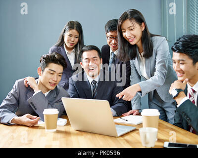 Une équipe de dirigeants d'entreprises asiatiques qui travaillent ensemble à l'aide de bureau ordinateur portable, heureux et souriant. Banque D'Images