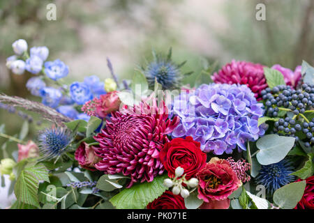 Arrangement de fleurs allongées en métal vintage vase. table. Couleur bleu et rouge. Superbe bouquet de fleurs différentes. Le parc historique Banque D'Images