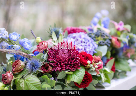 Arrangement de fleurs allongées en métal vintage vase. table. Couleur bleu et rouge. Superbe bouquet de fleurs différentes. Le parc historique Banque D'Images