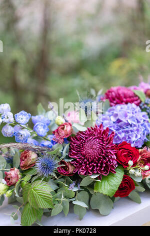 Arrangement de fleurs allongées en métal vintage vase. table. Couleur bleu et rouge. Superbe bouquet de fleurs différentes. Le parc historique Banque D'Images