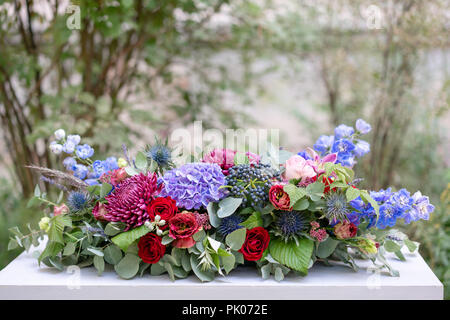Arrangement de fleurs allongées en métal vintage vase. table. Couleur bleu et rouge. Superbe bouquet de fleurs différentes. Le parc historique Banque D'Images