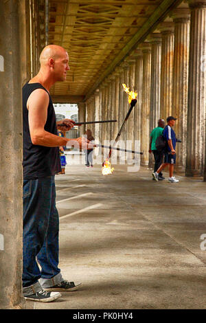 Artiste de rue jouant des bâtons de feu sous la colonnade près du musée privé de Berlin, Allemagne Banque D'Images