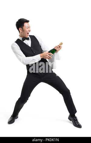 Cheerful young waiter acclamer avec bouteille de champagne Banque D'Images