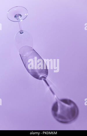Verre de vin vide inversé avec la réflexion de l'ombre sur fond violet. Copy space Banque D'Images
