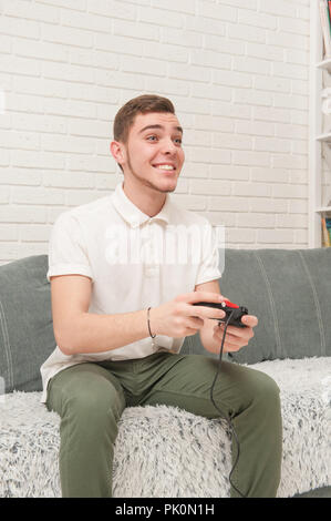 Un adolescent est assis sur le canapé et regarde la télévision Banque D'Images