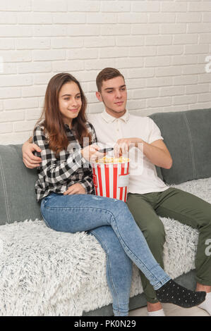 Deux adolescents sont assis sur le canapé à regarder la télévision et eating popcorn Banque D'Images