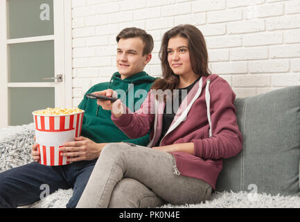 Deux adolescents sont assis sur le canapé à regarder la télévision et eating popcorn Banque D'Images