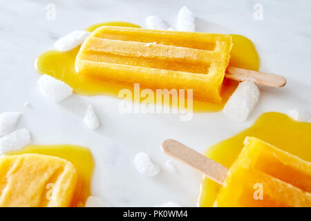 Lollty crème glacée Orange. La fonte de la crème glacée aux fruits avec des touches et de la glace sur une table en marbre gris avec copie espace. Dessert d'été Banque D'Images