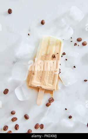 Gelato pop avec mascarpone, chocolat au lait et le tiramisu ingrédients avec les grains de café sur une baguette de bois sur de la pierre, vue de dessus de table glacé Banque D'Images