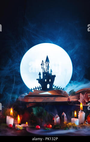 Concept d'Halloween avec un château hanté silhouette devant la pleine lune. Livre de sorts sur sorcière ou un assistant de travail. Toujours sur la vie magique de création Banque D'Images