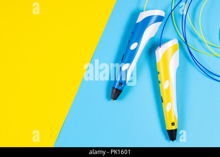 Stylos 3d avec filament de plastique colorés sur fond jaune et bleu. Banque D'Images