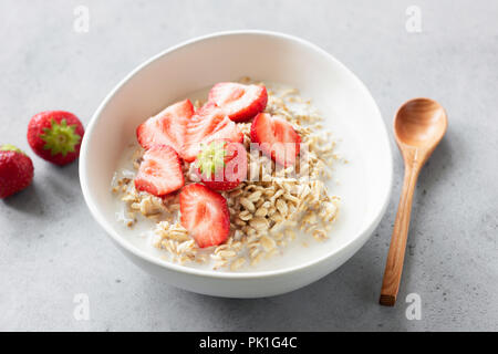 Bouillie d'avoine ou à l'avoine avec des fraises dans le bol sur fond de béton. Petit-déjeuner sain, les régimes alimentaires, perte de poids ou d'enfants food concept Banque D'Images