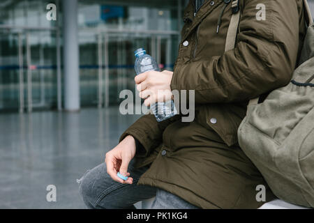 Le voyageur est titulaire d'une bouteille d'eau dans sa main. La personne se repose avant que d'autres randonnées. Banque D'Images