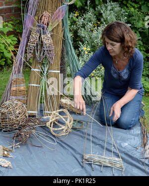 Petit Saule sculptures sont exposées en face d'une variété de tiges d'osier avec l'artiste Sara Holden Banque D'Images