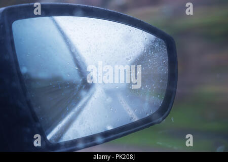 Location de voiture en pluie. gouttes sur rétroviseur latéral en jour de pluie Banque D'Images