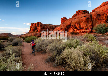 Une femme monte un vtt le Chuckwalla sentier dans la falaise rouge désert réserver près de Saint George, Utah, USA. Banque D'Images