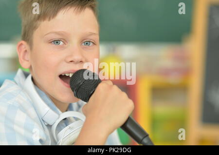 Portrait of boy singing karaoke at home Banque D'Images