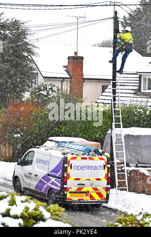 Scène de rue neige hiver BT openreach van & engineer man white casque Veste haute visibilité l'échelle travailler sur la réparation des lignes de téléphone à domicile de l'England UK Banque D'Images