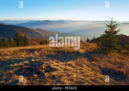 Vue spectaculaire des collines de smoky mountain range couvert de brouillard gris violet ; pierres abandonnées de camping cheminée sous un ciel sans nuage bleu sur wa Banque D'Images