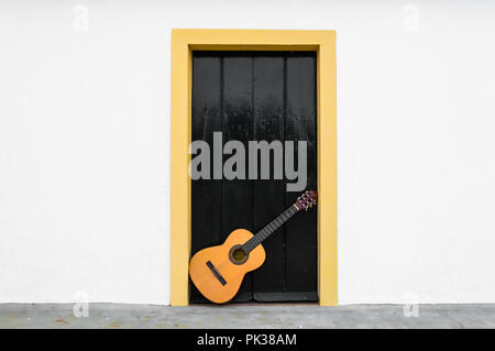 L'espagnol ou la guitare classique reposant sur une porte d'un patio andalou. Une scène d'un instrument de musique dans le mur blanc d'une maison rurale. Banque D'Images