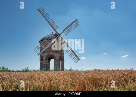 Un moulin à vent se trouve dans le soleil d'été. Situé en haut d'une colline et entourée de blé. Banque D'Images