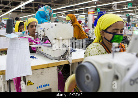 Une travailleuse du vêtement au travail sur une machine à coudre à l'intérieur d'une usine de confection au Bangladesh. Banque D'Images