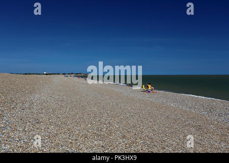 Les vacanciers de soleil vous détendre sur une chaude journée d'été à la plage de galets à Aldeburgh, Suffolk, UK Banque D'Images