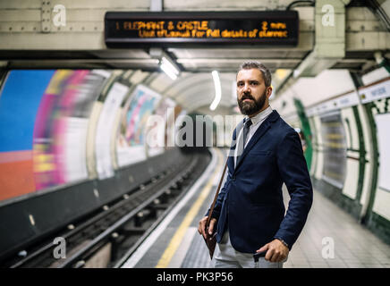 Homme d'Hipster avec un sac attendant le train en métro. Banque D'Images