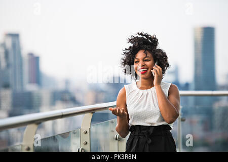 Une businesswoman standing contre Londres vue panorama, de passer un appel téléphonique. Banque D'Images