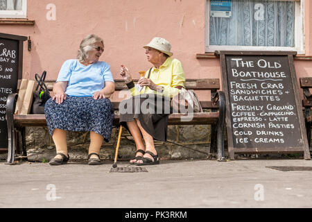 Deux dames sont profondes dans la conversation sur un banc tout en profitant du soleil au bord de mer à Lyme Regis dans le Dorset de l'Ouest. Banque D'Images