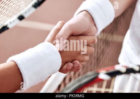 Se serrer la main après un bon jeu. Close-up de l'homme et de la femme en serrant la main bracelet sur le filet de tennis Banque D'Images