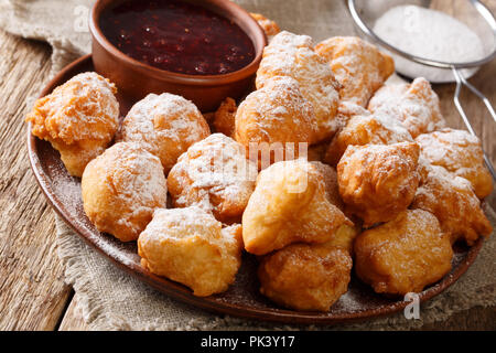 Frite faite maison petulla avec confiture de framboises et de sucre en poudre sur une assiette sur une table horizontale. Banque D'Images