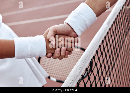 Se serrer la main après un bon jeu. Close-up de l'homme et de la femme en serrant la main bracelet sur le filet de tennis Banque D'Images