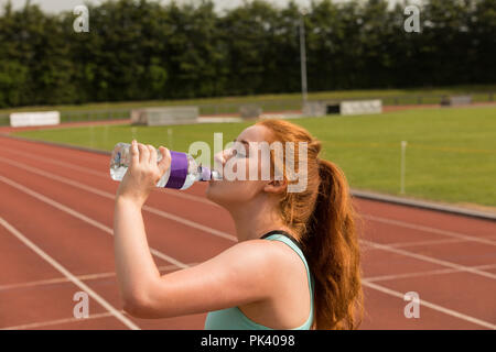 Athlétisme féminin l'eau potable sur une piste de course Banque D'Images