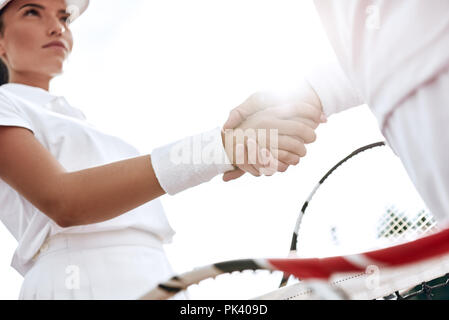 Se serrer la main après un bon jeu. Close-up de l'homme et de la femme en serrant la main bracelet sur le filet de tennis Banque D'Images