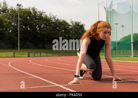 Athlète féminin prêt à fonctionner sur une piste de course Banque D'Images