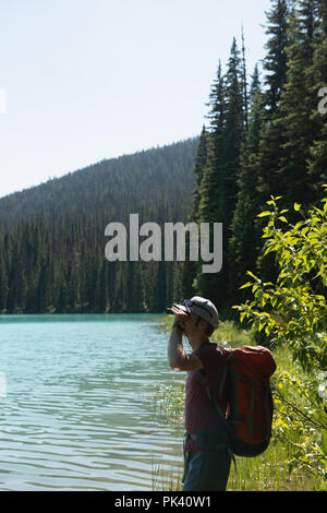 Male hiker binoculars près de Riverside Banque D'Images