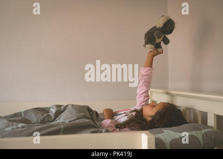 Girl Playing with teddy bear on bed Banque D'Images