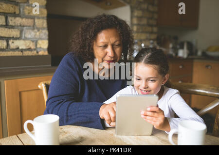 Grand-mère et petite-fille using digital tablet in kitchen Banque D'Images