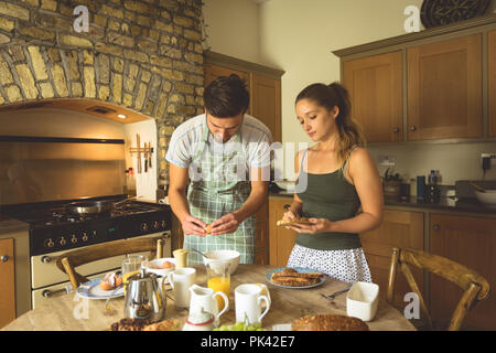 Couple en train de préparer le petit-déjeuner sur une table à manger Banque D'Images