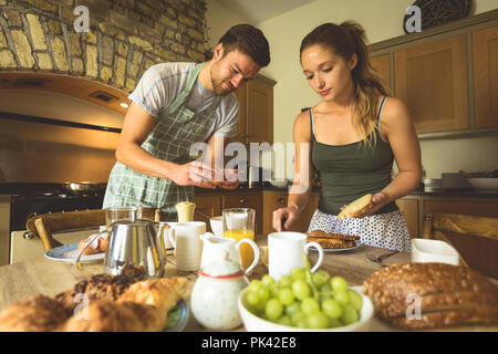 Couple en train de préparer le petit-déjeuner sur une table à manger Banque D'Images