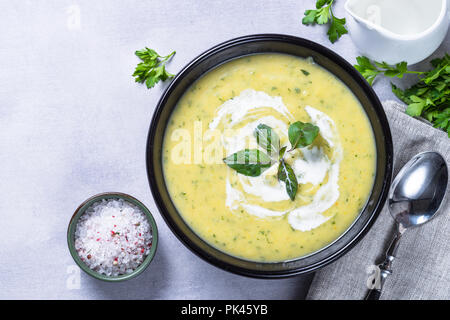 Soupe crème de courgettes purée dans un bol noir. Plat végétarien. Vue d'en haut. Banque D'Images