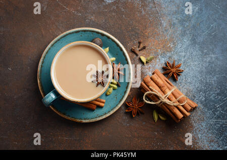 Indian masala thé chai. Thé au lait épicé foncé sur fond rouille. Banque D'Images