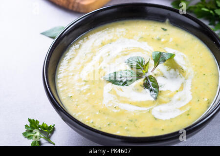 Soupe crème de courgettes purée dans un bol noir. Plat végétarien. Banque D'Images