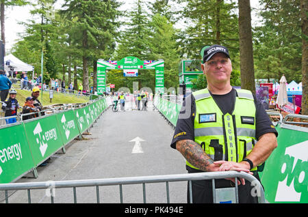 Stage 6 Tour de Bretagne 7 septembre 2018, Whinlatter. Cheerful security guard manning une barrière par la ligne d'arrivée avant le départ de la course. Banque D'Images