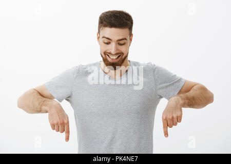 Portrait de heureux et surpris beau mâle masculin avec barbe et coiffure parfaite à la pointe vers le bas et avec délice et curiosité profiter de regarder vers le bas à intéressant copy space Banque D'Images