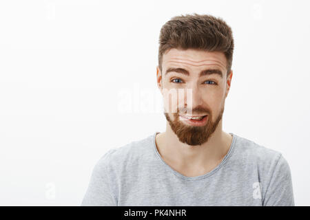 Gros plan de culpabilité mignon petit ami avec barbe et sourcils brun hairstyle sensibilisation essayant des excuses pour faire erreur disant désolé sentiment confus et maladroit contre fond blanc Banque D'Images